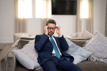 Sad man with laptop got migraine touches her head because of pain. Man manager with strong headache. Overworked freelancer or manager at office.