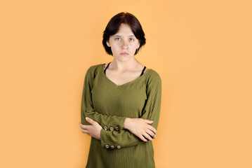 Pretty self-confident but sad teenage girl on an orange background, the girl is having a hard time...
