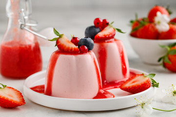 Strawberry panna cotta with berry sauce decorated with fresh berries on a white plate. Summer healthy dessert. Selective focus. © Olga Romankova