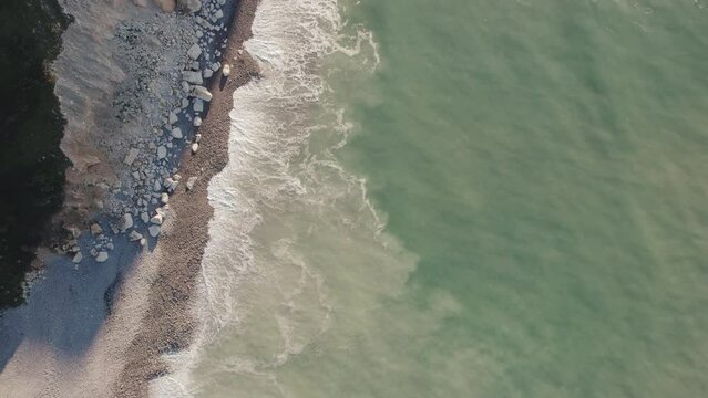 Aerial of impressive Normandy's white cliffs, round pebbles beaches and green pasture on the Alabaster Coast, France, 4K drone