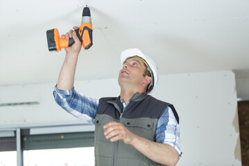 handyman using a cordless drill on the ceiling