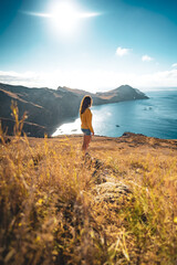 Back view of a tourist on a hill, overlooking the coastal landscape of Madeira Island in the Atlantic Ocean in the morning. São Lourenço, Madeira Island, Portugal, Europe.