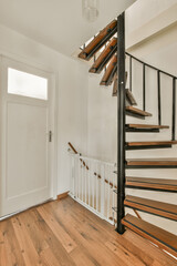 a staircase in a house with wood flooring and white walls on either side, there is an open door leading to the room