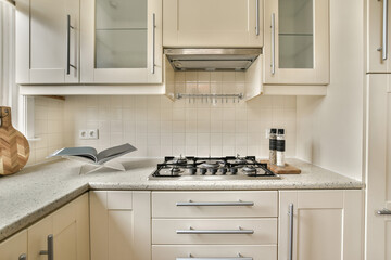 a kitchen with white cupboards and appliances on the counter top in front of the stove, which is being used for cooking