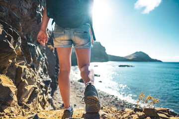 Tourist legs walk down stairs to the beach overlooking the coastal landscape of Madeira Island and...