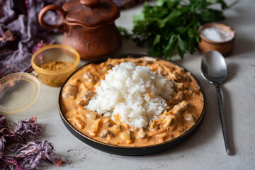 Family dinner. A dish for the whole family: pork goulash with sauce and boiled rice on a beautiful plate. Close-up. A hearty lunch.