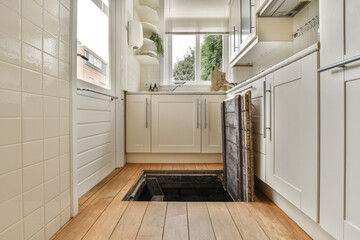 the inside of a kitchen with wood flooring and white cupboards on either side of the door to the room