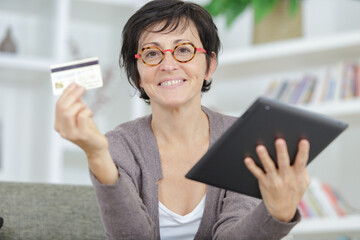 portrait of mature woman holding caredit card and tablet