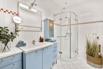 a modern bathroom with blue cabinets and white tiles on the walls, along with a plant in a basket next to the sink