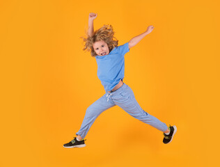 Fototapeta na wymiar Kid boy jump fly movement wear shirt and jeans isolated on yellow studio background.