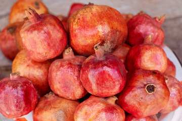 A pile of ripe juicy red pomegranates lies on a counter at a food market