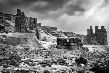 Black and white landscape of dark storm clouds engulfing the arid desert landscape of Arches National Park Utah.