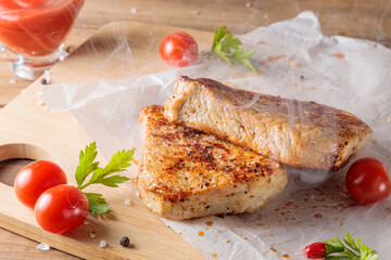 Slices of roast pork meat with tomato and ketchup on a wooden board.