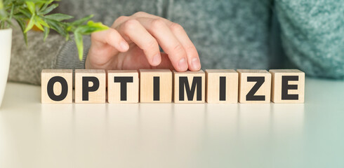 Optimize - word in wooden cubes, Business solution text and Hand.