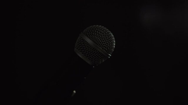 Close up shots microphone on stage with spotlight strike through the darkness background.