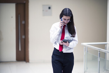 businesswoman talking by phone in office, working with tablet