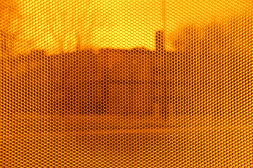 Image of micro perforated orange texture, in the background you can see distorted silhouettes