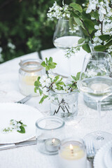 Rustic zero waste wedding decor with natural elements. Fresh spring blooming flowers, candles, linen napkins, wine glasses. Eco friendly decoration for the special holiday dinner. Romantic cozy place