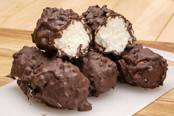 Natural dessert cottage cheese in chocolate with walnuts on a wooden table. 