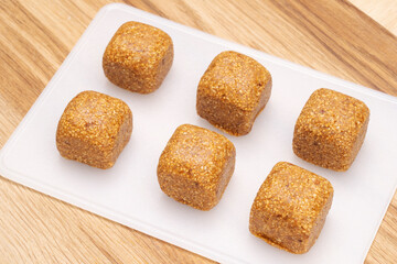 Energy balls candies made from natural products, square shape, on a cutting board. 