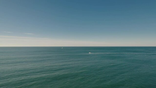 Aerial of the sea in Normandy's Alabaster Coast with a little fishing boat crossing, France 4K drone