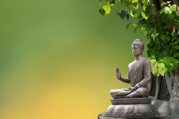 Buddha statue sitting under the bodhi tree on nature background.