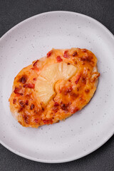 Grilled chicken fillet in the form of a steak with tomatoes, pineapple and cheese