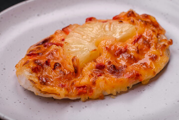 Grilled chicken fillet in the form of a steak with tomatoes, pineapple and cheese