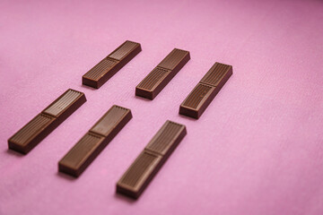 Broken milk chocolate on pink background.