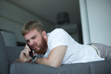 Portrait of young angry sad upset frustrated man, dissatisfied unhappy guy talk, swear on cell...