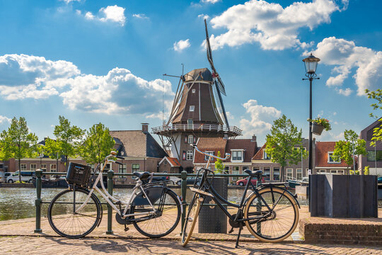 A typical dutch scene with traditional windmill and bikes along the canal in the city of Meppel on a sunny spring day