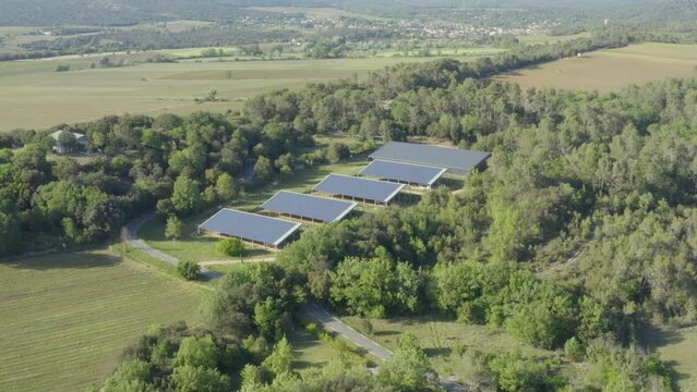 Aerial shot approaching a solar panel farm nestled in a forest in the countryside