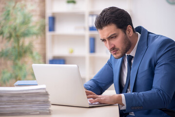 Young male employee and too much work in the office