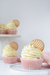 Pink cupcakes with tall american buttercream swirl and cookie garnish, cupcakes in pink liners with a tall vanilla buttercream and a cookie, birthday cupcakes on a white background