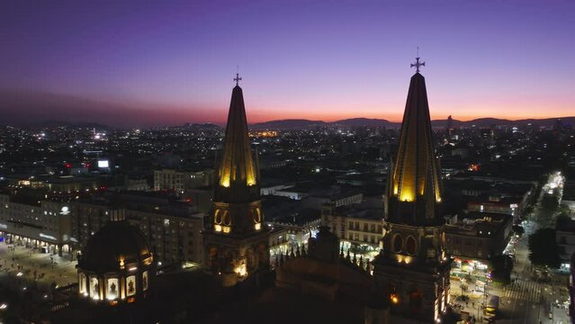 Beautiful purple pink sunset sky above Guadalajara city in Mexico. Drone of historic architecture Cathedral with night illumination. Aerial Guadalajara Cathedral and Central Plaza Jalisco. Latin city