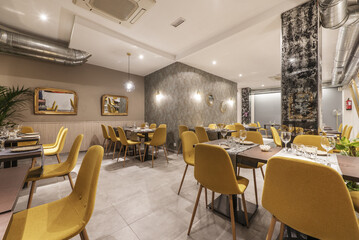 Fototapeta na wymiar dining room of a restaurant with wooden tables, yellow upholstered chairs