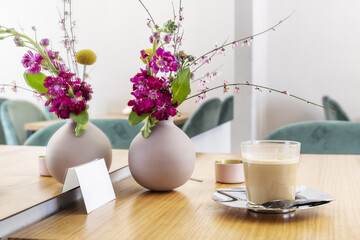 A centerpiece with flowers and a latte