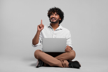 Smiling man with laptop on light grey background, space for text