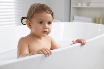 Cute little girl taking bath at home