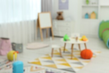 Blurred view of child`s playroom with different toys and furniture. Stylish kindergarten interior