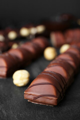 Tasty chocolate bars and nuts on black table, closeup