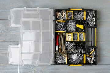 Box with different furniture fittings and tools on rustic wooden table, top view