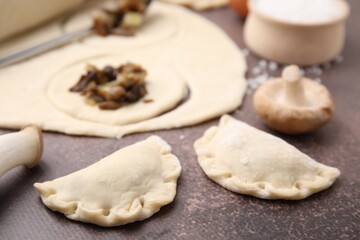 Fototapeta na wymiar Process of making dumplings (varenyky) with mushrooms. Raw dough and ingredients on grey table, closeup