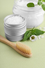 Fototapeta na wymiar Toothbrush, dental products and herbs on light olive background, closeup