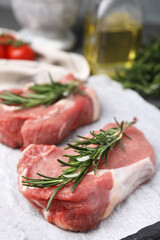 Fresh raw meat with rosemary on parchment paper, closeup