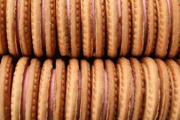 Tasty sandwich cookies with cream as background, top view