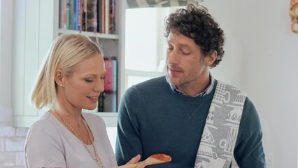 Happy couple cooking, taste food and making meal, lunch or dinner in kitchen at home. Smile mature woman giving man a taste of homemade sauce, spaghetti or pasta to enjoy eating together - Powered by Adobe