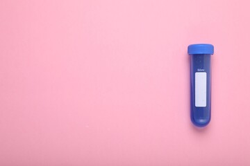 Test tube with liquid on pink background, top view and space for text. Kids chemical experiment toy