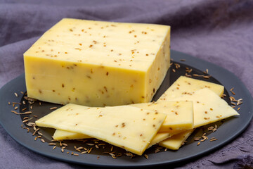 Cheese collection, piece of cow milk Dutch gouda cheese with dried aromatic cumin seeds close up