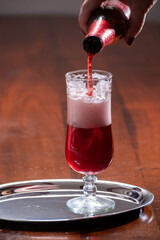Pouring of Belgian fruity red sour cherry kriek beer in glass